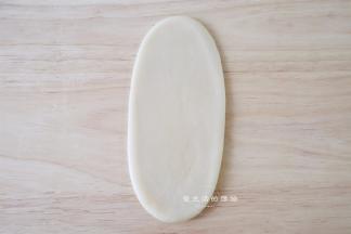 取一个面团，收口朝上，擀成对12CM的长舌状。