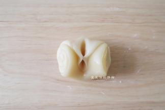 取一个面团，将两边朝中间捏起来，用擀面杖擀成中间厚一些的面片，