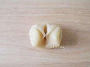 取一个面团，将两边朝中间捏起来，用擀面杖擀成中间厚一些的面片，