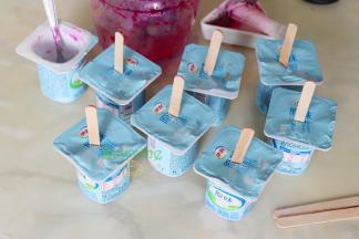 在酸奶盖子中央，用剪刀剪一个口，把冰棍棒插入酸奶里。放入冰箱冷冻1小时取出，脱模即可吃。