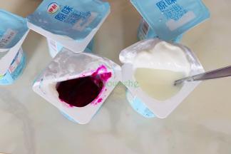 酸奶杯从冰箱取出，打开杯子的一半口，倒出半杯酸奶，接着倒入半杯火龙果汁。