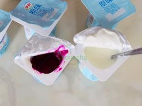 酸奶杯从冰箱取出，打开杯子的一半口，倒出半杯酸奶，接着倒入半杯火龙果汁。