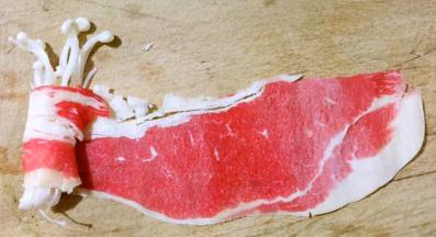 取一片肥牛轻轻展开铺平一小把金针菇放在肥牛的一端顺一个方向卷起