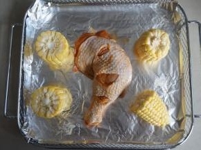 把腌制好的鸡腿放在烤篮上（烤篮铺上一张锡纸，防止油滴落在发热管上），玉米切成四段，用有盐黄油抹一下玉米，这样烤好的玉米更好吃