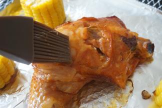 把烤篮取出，在鸡腿和玉米表面均匀刷上蜂蜜，把温度调到200度，继续烘烤5分钟