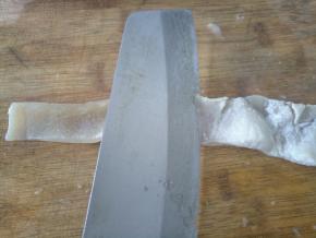 煮好的猪皮捞起，将猪皮上的肥肉削掉。