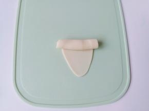 水油皮放在手心，包裹上油酥，慢慢推水油皮把油酥包上，收口揉圆放在案板上，用擀面杖擀面杖擀成如图形状再从上到下卷起来。