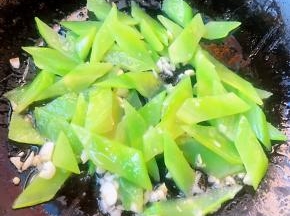 锅中倒入底油加热放入蒜粒爆香再放入莴笋片炒匀