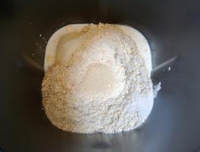 接下来加入高筋面粉和水果麦片，糖和盐对角放，面粉中间挖个小洞放入干酵母，用面粉盖上，选择面包机的“自动和面”程序15分钟。