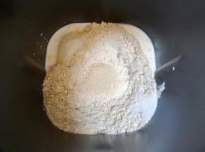 接下来加入高筋面粉和水果麦片，糖和盐对角放，面粉中间挖个小洞放入干酵母，用面粉盖上，选择面包机的“自动和面”程序15分钟。