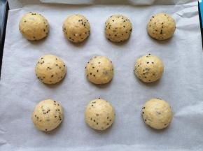 烤盘里铺上油纸，将面包面团滚圆放在油纸上。