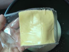 
搅拌均匀的牛奶糊过筛到锅里，加入一块芝士片