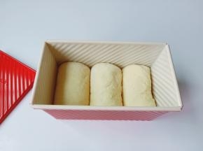 发酵好的面团均匀排气，分成三个面团，擀成长条从上到下卷起来放入阳晨吐司模具里面。