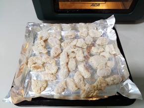 冷冻的半成品鸡米花取出，放铺了锡纸的烤盘上。