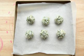 然后全部拌匀，用勺子取一大勺饭，放在戴好手套的手上，左右来回，攥出一个饭团，略微捏紧实一点，不然烤的时候会容易散开。排入垫了油纸的烤盘中。