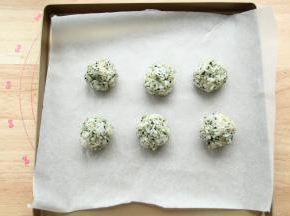 然后全部拌匀，用勺子取一大勺饭，放在戴好手套的手上，左右来回，攥出一个饭团，略微捏紧实一点，不然烤的时候会容易散开。排入垫了油纸的烤盘中。