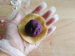 取一块面团，搓圆，然后放置在左手手心，用右手手掌部位去按压成中间厚，四周薄的圆形面片，也可以用擀面杖擀开！我习惯用手掌，好操作，和压月饼面皮方法是差不多的。然后放上一个步骤5准备好的馅料球。