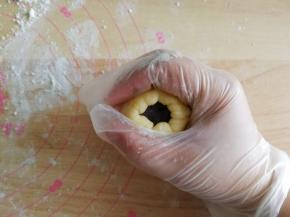 翻面，馅料在下，将面皮贴合在馅料球上，再翻回正面。左手四指托着面皮，大拇指压住馅料球，右手虎口配合将面皮往上收口。收口一定要收紧！一定要收紧！不能露馅，不然烤的时候容易爆口。