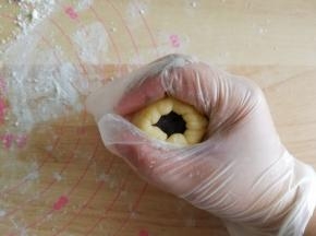 翻面，馅料在下，将面皮贴合在馅料球上，再翻回正面。左手四指托着面皮，大拇指压住馅料球，右手虎口配合将面皮往上收口。收口一定要收紧！一定要收紧！不能露馅，不然烤的时候容易爆口。