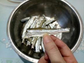 将泡小鱼干的水倒掉，用剪刀剪去鱼尾、鱼头、胸鳍什么的。