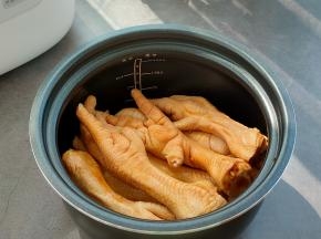 把腌渍好的鸡爪倒入电饭煲的内胆中。