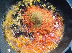 放入粗辣椒面和花椒面，继续小火翻炒至辣椒面冒油！