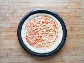 在饼底涂上番茄酱，撒上一层马苏里拉芝士。