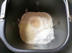 接下来加入高筋面粉和奶粉，糖粉和盐对角放，面粉中间挖个小洞放入干酵母，用面粉盖上，选择面包机的“自动和面”程序15分钟。