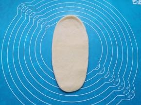 取一份面包面团擀成牛舌状。