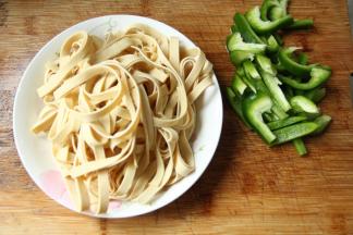 步骤1、千张清洗干净，然后叠在一起，从上往下卷起，然后切粗丝。青椒去柄去籽，然后也是切丝。