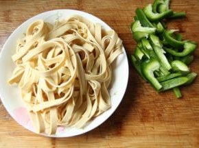 步骤1、千张清洗干净，然后叠在一起，从上往下卷起，然后切粗丝。青椒去柄去籽，然后也是切丝。