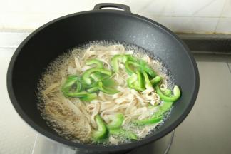 步骤3、中火煮一会，倒入青椒丝，和千张丝一起焯水，不需要焯水太久。焯熟断生，去除千张的豆腥味。