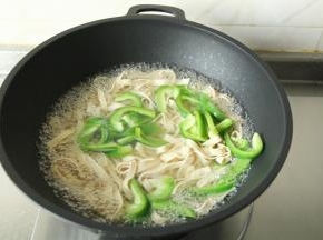 步骤3、中火煮一会，倒入青椒丝，和千张丝一起焯水，不需要焯水太久。焯熟断生，去除千张的豆腥味。