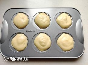 拌匀的面糊用汤匙或裱花袋挤入模具中，面糊略有剩余，装在一个小纸杯里一起烤。