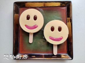 预留一点牛奶糊，放一点点紫薯粉拌匀，待娃娃头冷冻成型后取出脱模，眼睛部位挤上黑巧，嘴巴部位挤上紫薯牛奶糊，继续放冰箱冷冻一会。