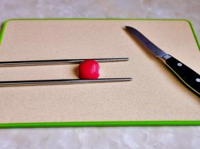 取一半萝卜，再切片，切记不要切段哈，可以借助两根筷子，再用刀切，如图所示。