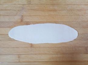 用擀面杖擀成薄薄的牛舌状。