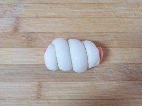 取半根火腿肠，将卷好的长条状面团缠绕在火腿肠上面，一个香肠馒头卷就做好了，依次做完剩下的馒头卷。