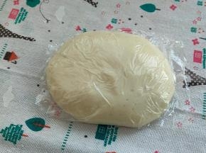 好的面团，它会挂在厨师机的钩子上，不会掉落的，我们用手撑开，可以看见面筋，但还没有连成一片，并没有形成大片的薄膜，所以我需要静止，让薄膜连起来，用保鲜膜把油皮包起来密封静置30分钟松弛。
