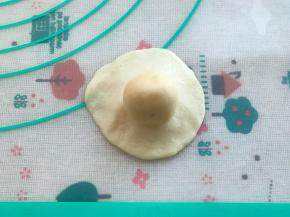 把水油皮按扁，油酥放在中间，把油酥完全包裹住，搓成圆团，收口朝下。
