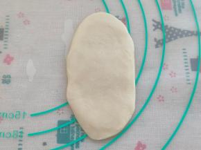 把面团按扁，擀成牛舌状。