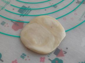 捏住两头往中间压一下，按扁，周围压的薄一点，中间稍稍厚一些。