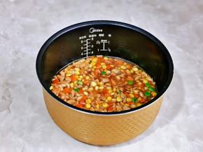 再把炒好的鸡肉时蔬倒在电饭煲中平铺，启动电饭煲煮饭模式即可。