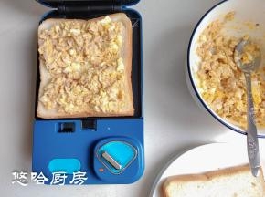 三明治早餐机先预热2分钟，放一片白吐司，吐司上面放适量的金枪鱼鸡蛋酱，不要太多，太厚的话会压不住。