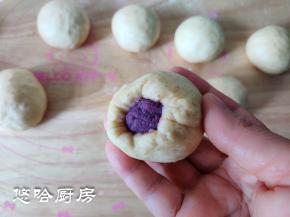 松弛后的面团拍扁、翻面，包入紫薯馅，捏紧收口，依次做好全部。