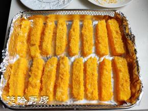 在炸蓝中铺一张锡纸，把沾满面包糠的牛奶条摆放在炸蓝中，牛奶条之间隔一点距离。