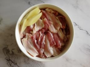 准备食材。清洗干净的五花肉，切成薄且均匀的片，码放在碗里，切上3片姜片。