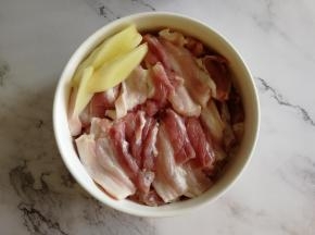 准备食材。清洗干净的五花肉，切成薄且均匀的片，码放在碗里，切上3片姜片。