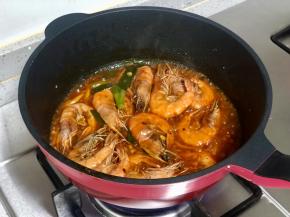 加入一小碗水，水沸后放入煎好的大虾，炒匀。