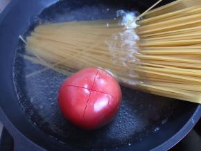 烧一锅水，下意面。番茄洗干净，顶上划一个十字，在锅里烫一分钟，注意番茄要翻几个身，这样烫得均匀，皮才容易剥下来。